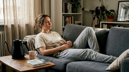 Kvinna lindrar mensvärk med värmedyna